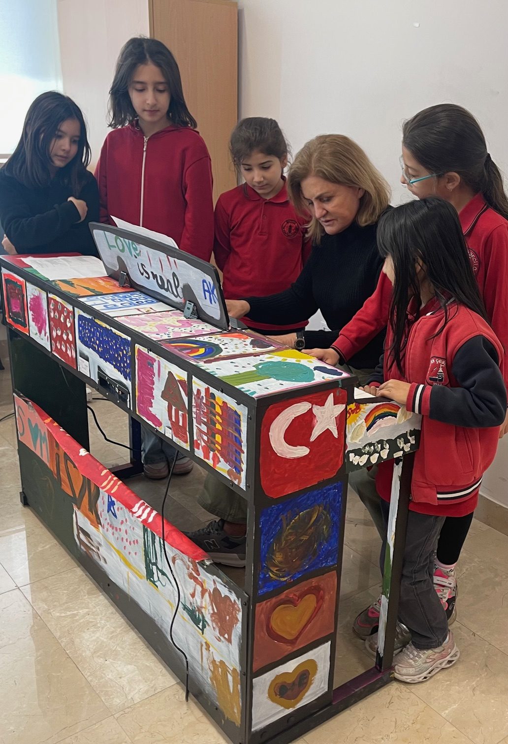 Öğrenciler ve öğretmenleri boyanmış piyano başında